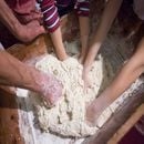 Hands of old lady and children making bread 