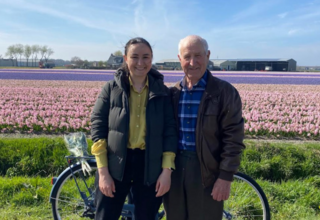 Oxana and her grandfather posing in front of a field of tulips.