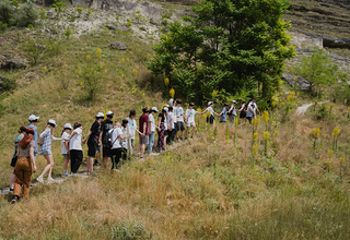 O linie de tineri ucraineni și moldoveni urcând pe poteca de munte cu ochii închiși într-un exercițiu de team-building