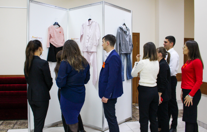 5 femei și 2 bărbați analizează hainele expuse în cadrul expoziției