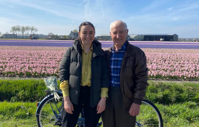 Oxana and her grandfather posing in front of a field of tulips.