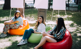 Trei fete adolescente sunt asezate in parc. 