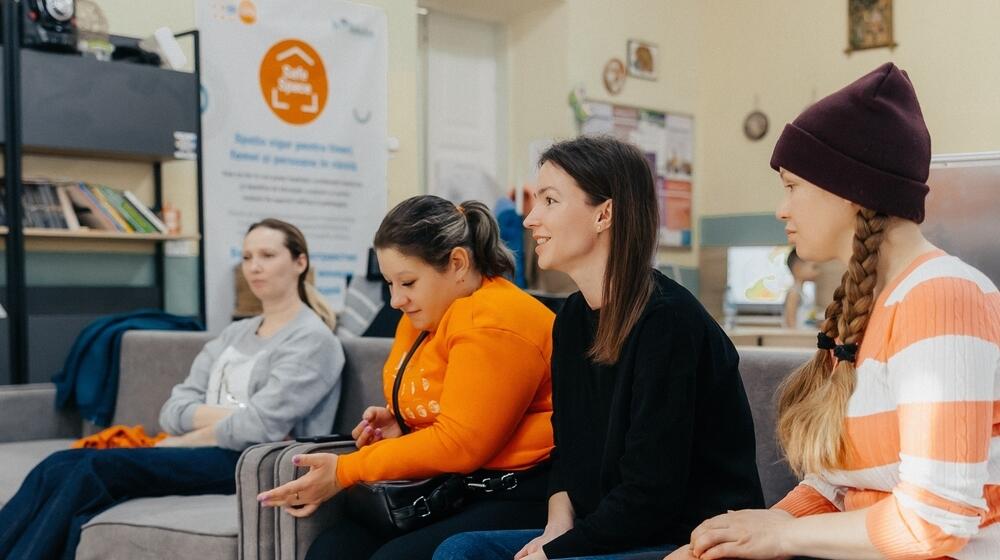 Four women sitting on a couch and engaged in a discussion at UNFPA Safe Space