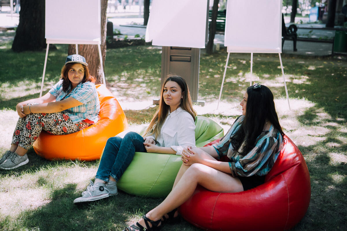 Trei fete adolescente sunt asezate in parc. 