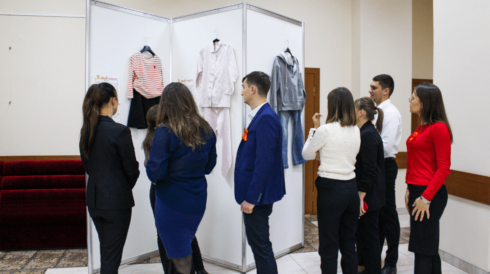 5 women and 2 men analyze the clothes exposed within the exhibition