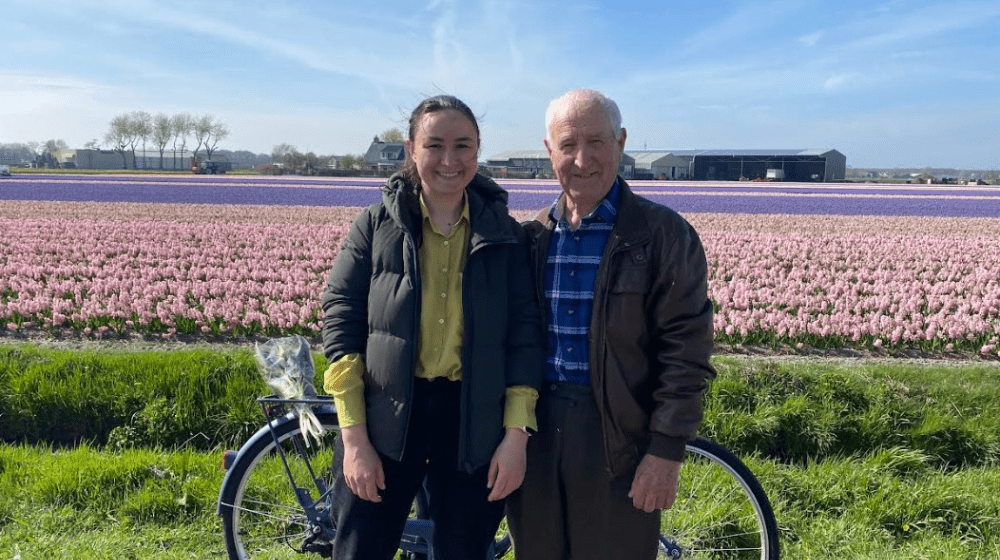 Oxana and her grandfather posing in front of a field of tulips.